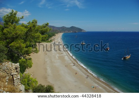 A composition with blue sky and still more blue sea: the photographer is standing on the hill, so we see the sandy coastline stretching to the mountains in perspective