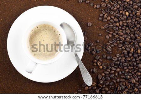Background with coffee beans and grounded coffee in composition with a cup of coffee with a spoon.