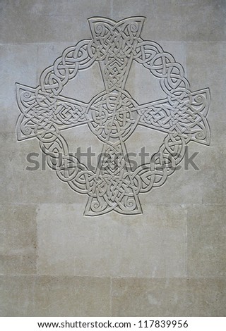 Celtic knot cross inscribed on stone wall with copyspace below