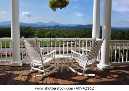 Two relaxing armchairs overlooking peaceful mountain view on porch of luxury resort hotel