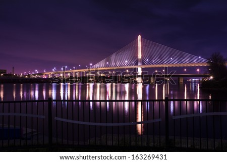 Night view of the Veterans\' Glass City Skyway bridge in Toledo Ohio.  The bridges center pylon is lit up with LED lighting and the stainless steel cables are lit with floodlights.