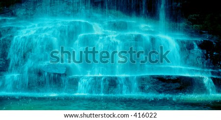 A horizontal photo of the splash down area of a beautiful waterfall. Given a blue tone for a cooling abstract effect.