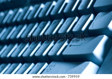 A macro of a keyboard with a blue tone and shadows from off camera  lighting. Lots of detail, you can see the raised letters in the  Shift key. Shallow depth of field with focus on the Enter key area.