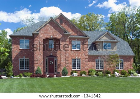 Beautiful red brick  home. Very colorful photo with blue sky and green grass. Typical new home in the suburbs of the United States. Just one of many home or house photos in my gallery.