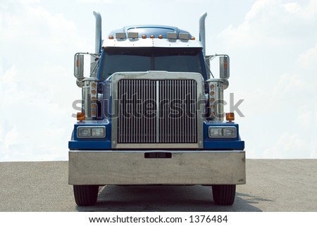 Front view of a blue 18 wheel semi truck with a blue sky background..