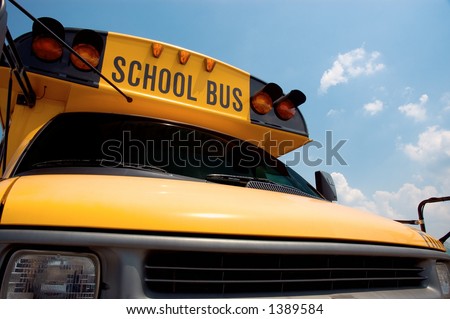 Close-up of the front of a school bus with a blue sky background.