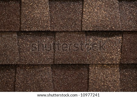 A close-up of brown toned architectural style asphalt roofing shingles.