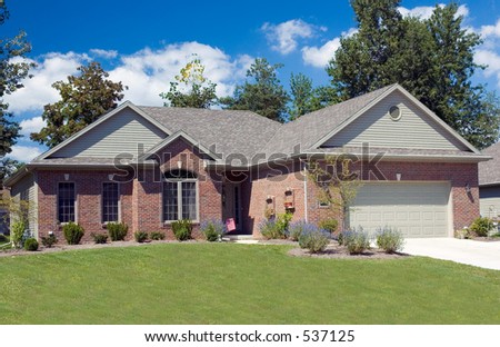 beautiful brick ranch home against a blue cloudy sky stock photo