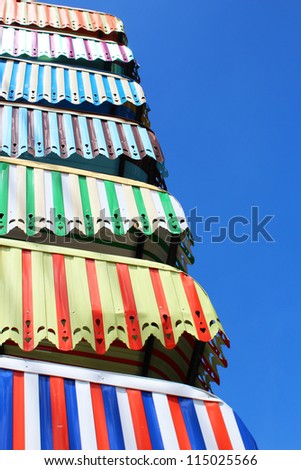Colorful sun blinds for sale under a blue sky in Thailand.