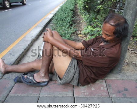 BANGKOK, THAILAND - DECEMBER 17 : Thai old homeless man sleeps on the roadside December 17, 2005 in Bangkok.