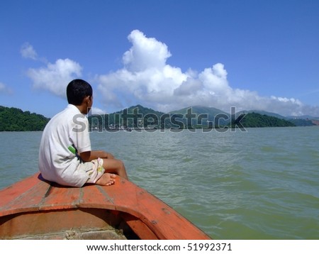 Boy sits on a boat front while crossing the Thai, Burma border.