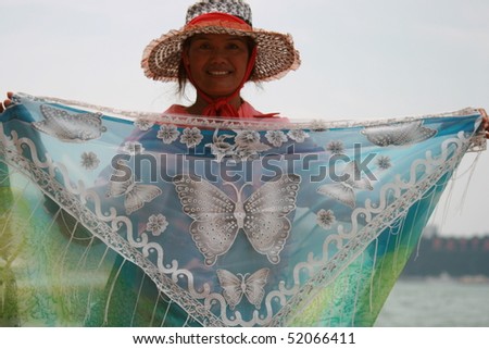 PATTAYA, THAILAND - OCTOBER 20: Thai lady shows her patterned fabric sheet for sale to tourists on South Pattaya beach. October 20 2008 in Pattaya.