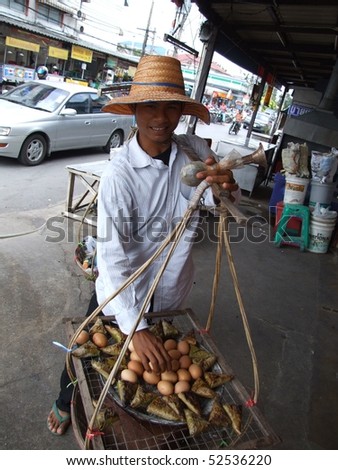 BANGKOK, THAILAND - OCTOBER 30: Thai man carries cooked eggs and wrapped sweet Thai food in baskets for sale to pedestrians October 30, 2005 in Bangkok.