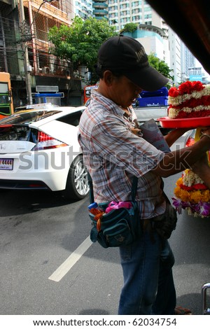 BANGKOK - SEPTEMBER 24: Thai man sells Buddhist flowers on the road on September 24, 2010 in Bangkok, Thailand.