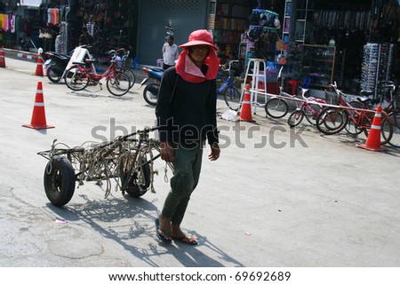 POI PET, THAILAND - JANUARY 19: Man pulls a cart along the road on January 19, 2011 in Poi Pet, Thailand.