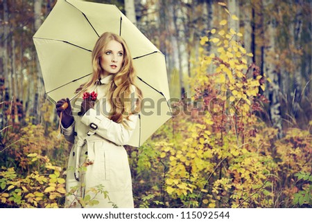 Fashion portrait of a beautiful young woman in autumn forest. Girl with umbrella