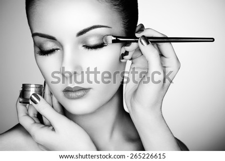 Makeup artist applies eye shadow. Beautiful woman face. Perfect makeup. Black and white