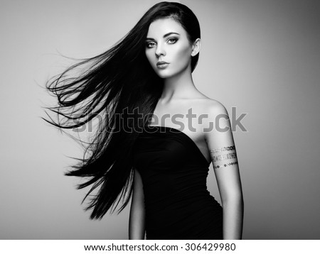 Fashion portrait of elegant woman with magnificent hair. Brunette girl. Perfect make-up. Girl in elegant dress. Flash tattoo gold. Black and white