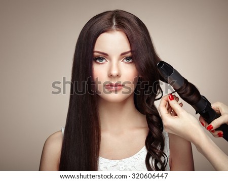 Hairdresser woman curls her hair. Portrait of young beautiful girl with luxurious hair. Fashion and beauty. Perfect make-up