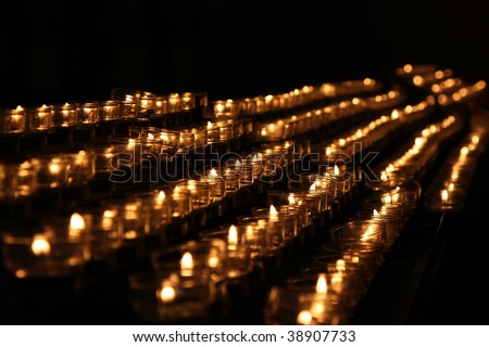 The burning church candles rowed on black background.