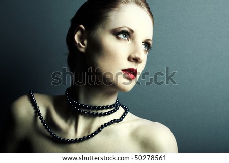 The beautiful young girl with a dark blue beads on a neck