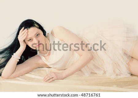 The young woman lies on a floor in a romantic dress