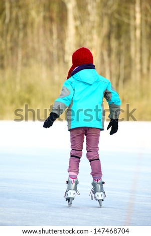 Ice skating girl. Young woman skating on ice with figure skates outdoors in the snow.