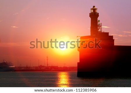 Cargo sea port. Old lighthouse. Sea cargo cranes. Sunrise.