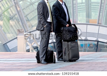 Two businessman with a business luggage. Urban scene.