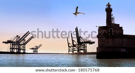 Cargo sea port. Old lighthouse. Sea cargo cranes.  Sunny day. Panorama.