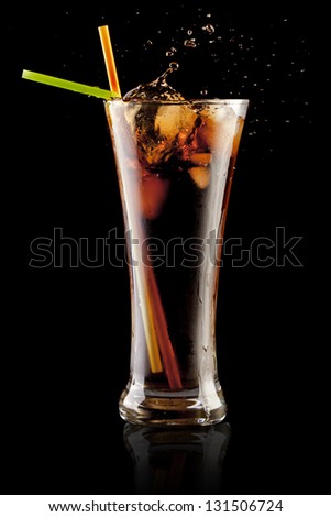 fresh cola juice and ice cubes splash in a glass on black background