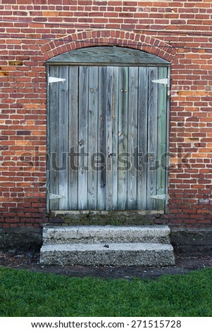 wood plank double doors at rustic brick building