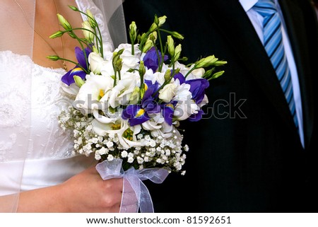 bride with  bouquet  with white  and blue flowers near groom with black suit and blue tail detail