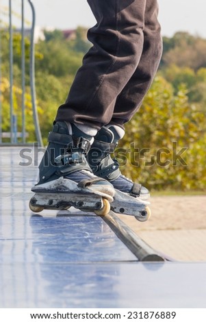 Teen with roller skates performing a stunt on a half pipe ramp in a hot day.