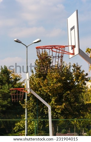 Outdoor basketball baskets in a row with chain nets in a sunny day.