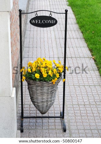 Basket with yellow violets in wrought iron frame, saying welcome
