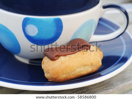 Mini chocolate choux pastry with blue decorated cup and saucer
