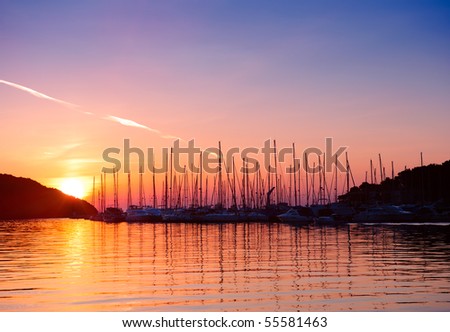 Sunset in Adriatic sea bay. Yacht silhouettes and calm water in sunset light