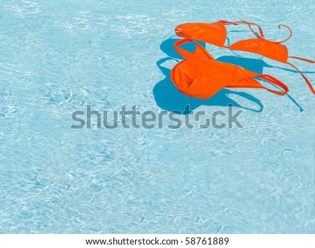 Orange bikini in clean water. Swim suit floating in a swimming pool. Copyspace background.