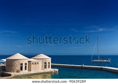 Adriatic sea coast of Croatia. Scenic view with yacht and typical Dalmatian styled stoned huts: bunja (trim, kazun). Hvar island.
