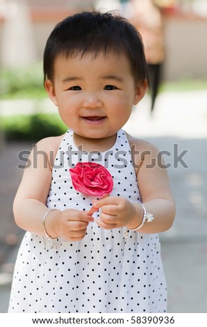 a beautiful one-year-old girl in dotted dressdress with her grandma standing behind her