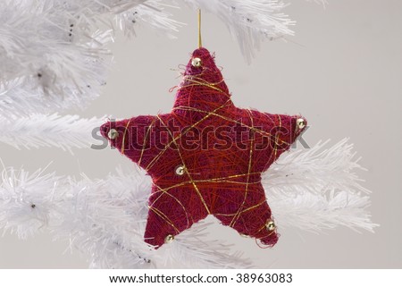 Red Christmas star hanging on white Christmas tree. White background.