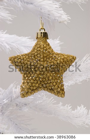 Golden Christmas star hanging on white Christmas tree. White background.