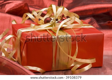 Golden Christmas gift box on red background.