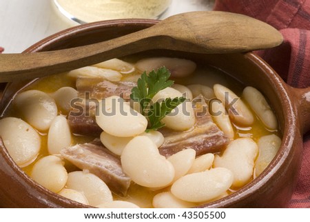 Beans and bacon stew served in a casserole dish. Spanish cuisine. Selective focus. Judiones de la Granja.