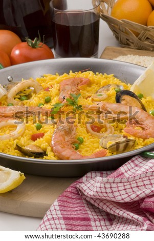 Spanish Cuisine. Paella. Spanish rice with red wine and oranges in background. Selective focus.