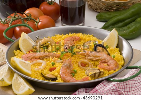 Spanish Cuisine. Paella. Spanish rice with red wine and oranges in background. Selective focus.