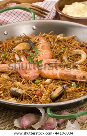 Spanish cuisine. Fideua. Seafood spaghetti cooked in a typical paellera, served with garlic mayonnaise sauce.