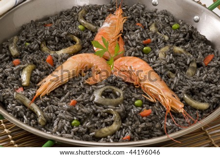 Spanish cuisine. Arroz negro. Black rice cooked in squid ink. Served in a typical paellera.