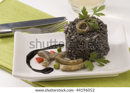 Spanish cuisine. Arroz negro. Black rice cooked in squid ink. Served in a white plate.